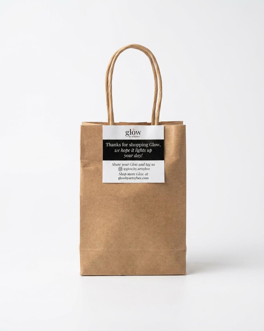 Brown paper bag with Thank You for Shopping Glow card stapled.
